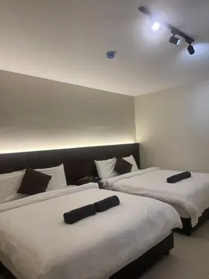 two beds in a room with white sheets and black pillows at Kangsar KK Hotel in Kuala Kangsar
