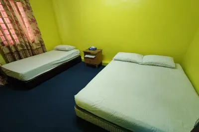 a small room with two beds and a night stand at D'BJ Motel in Bayan Lepas