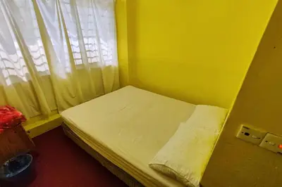 a small bed in a yellow room with a window at D'BJ Motel in Bayan Lepas