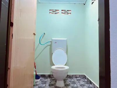 a bathroom with a white toilet in a room at Inap Desa R'Sawit - A dan B in Sekincan