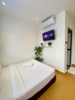 a white room with a bed and a flat screen tv at The 6N by Sky Hive in George Town