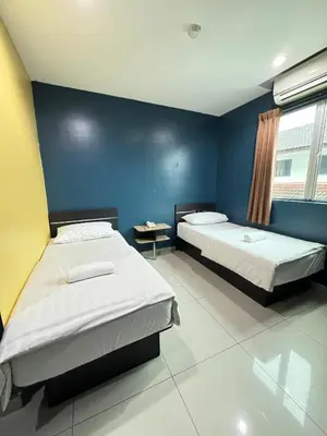 a bedroom with two beds and a blue wall at Hotel Pinji Ipoh in Ipoh