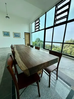 a large wooden table with chairs in a room with large windows at Ferringhi Inn 51 in Batu Ferringhi