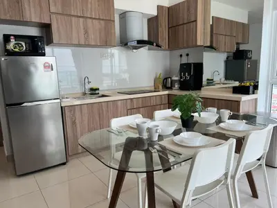 a kitchen with a glass table and a stainless steel refrigerator at Mansion One at Gurney Drive Georgetown by 3C in George Town