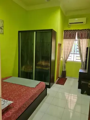 a bedroom with a bed and a green wall at de'berah homestay penaga in Penaga