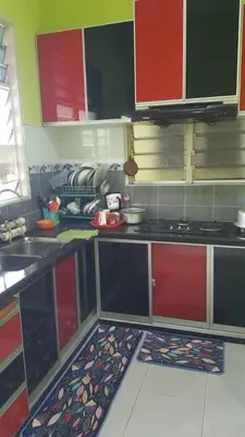 a kitchen with red and green cabinets and a stove at de'berah homestay penaga in Penaga