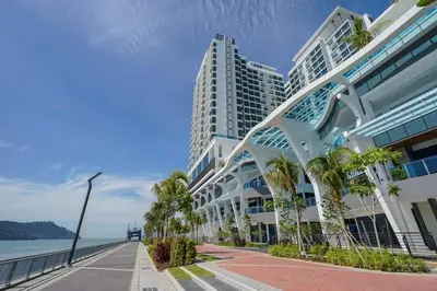 a building with palm trees in front of the ocean at cozy,Bayan,lepas 4pax1car ParkSpiceAirPort domestic guest only in Bayan Lepas