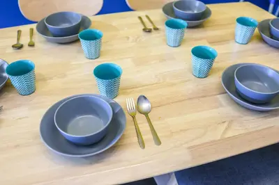 a wooden table with blue plates and utensils on it at Minion Family Adventure Homestay in Cameron Highlands Clover Home 6-30 in Brinchang