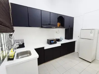 a kitchen with black cabinets and a white refrigerator at 9pax -Taman Bagan Butterworth -Budget Homestay in Butterworth