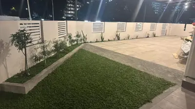a garden with a lawn and a white wall at Jambul Villa 3-storey corner House 6Bed5Bathroom in Bayan Lepas