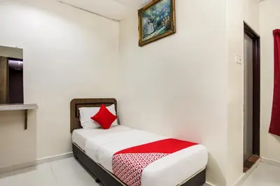 a small bedroom with a bed with a red pillow at Super OYO 89427 Kavanas Hotel Taiping in Taiping