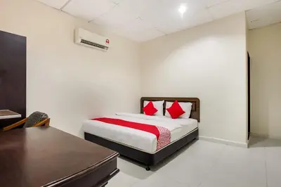 a bedroom with a bed with red pillows and a desk at Super OYO 89427 Kavanas Hotel Taiping in Taiping