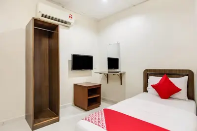 a bedroom with a bed with a red pillow and a tv at Super OYO 89427 Kavanas Hotel Taiping in Taiping