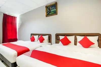 two beds in a room with red and white pillows at Super OYO 89427 Kavanas Hotel Taiping in Taiping