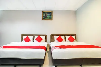 two beds in a room with red and white pillows at Super OYO 89427 Kavanas Hotel Taiping in Taiping