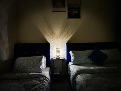 a bedroom with two beds and a lamp on a night stand at Premium Familystay Urban Suites-3BR 14 pax in Jelutong