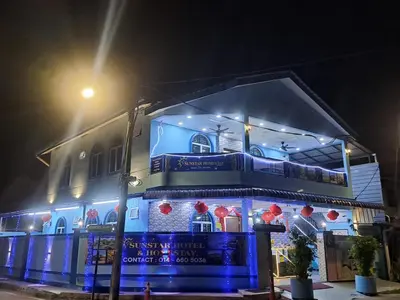a blue building with red decorations on it at night at SunStar Hotel in Kampong Batu Maung