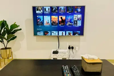a flat screen tv hanging on a wall with two remote controls at Georgetown Seaview 5 Min To Gurney N Straits Quay Washing Machine N Dryer in Tanjong Tokong