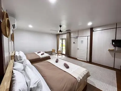 a bedroom with two beds and a tv and a door at Farmstay Laman Zulfaqar in Lahat
