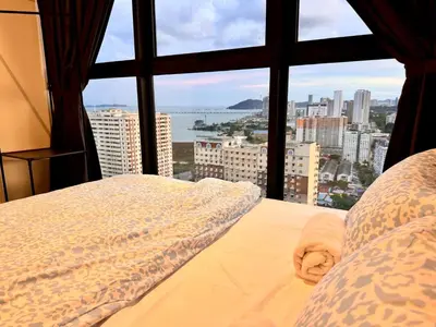 a bed in a room with a view of a city at Big Family stay urban Large Pool & Sea view Netfix in Jelutong