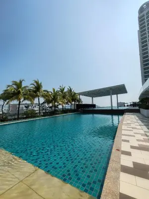 a swimming pool with palm trees and a building at Southbay Seaview Condo A2 10minQueensbay 10minSpice in Bayan Lepas