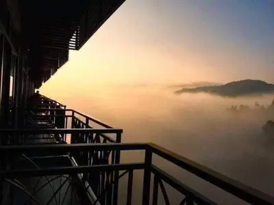 a view from a building of a foggy overlook with the sun rising in at Cameron Nova Highlands Resorts III in Brinchang
