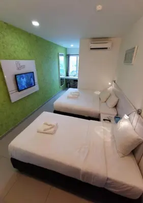 two beds in a room with green walls at Yew Boutique Hotel in Teluk Intan