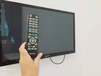 a person holding a remote control in front of a television at Yarra SP Homestay in Sungai Petani