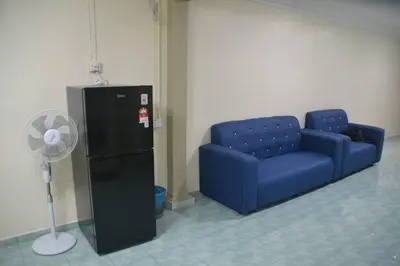 a blue couch and a fan in a room at Yim's Homestay in Kuala Kubu Baharu