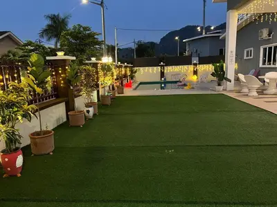 a backyard with a lawn with plants and a pool at Legreene Ipoh 15pax in Tambun
