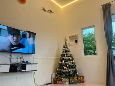 a christmas tree in a living room with a tv at Legreene Ipoh 15pax in Tambun