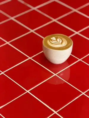 a cup of coffee sitting on a red tiled floor at Aayu Seckchuan - 3 mins walk to Love Lane in George Town
