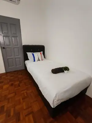 a bedroom with a bed with white sheets and a door at Busybee Breezy Stay Homestay in Ipoh