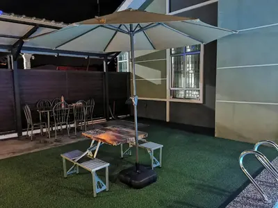 a table and chairs with an umbrella in a room at Teratak Dusun NadzYan in Bukit Selambau