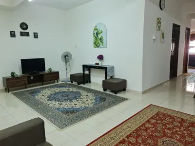 a living room with a table and a rug at Azam Homestay in Seri Manjung