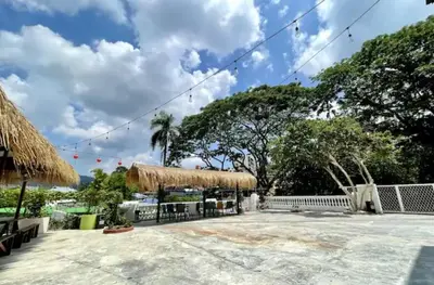 a large patio with a thatched building and trees at Kek Lok Si Inn in Ayer Itam