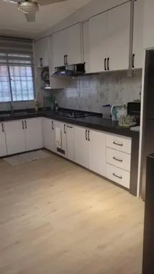a kitchen with white cabinets and a wooden floor at Ummi Homestay in Kampong Batu Tiga
