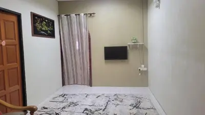 a room with a shower and a television on a wall at Ummi Homestay in Kampong Batu Tiga