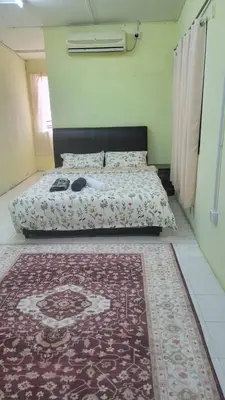 a bedroom with a bed with a rug on the floor at Ummi Homestay in Kampong Batu Tiga
