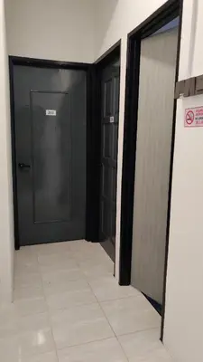 a hallway with two black doors and a tile floor at 23 Inn Queenbed Room with share bathroom in Simpang Ampat