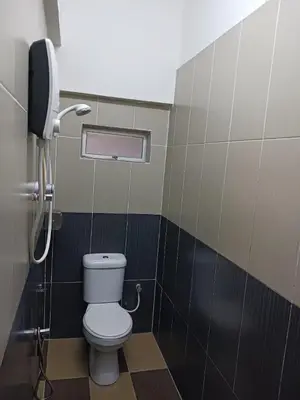 a bathroom with a toilet and a phone at Hotel Kavanass Inn in Simpang