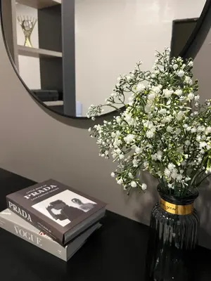 a vase of flowers on a table next to a mirror at AbelHome in Teluk Intan