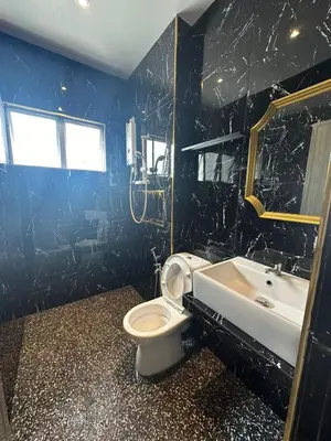 a bathroom with a white toilet and a sink at Adik aisyah Cameron Black Pink in Tanah Rata