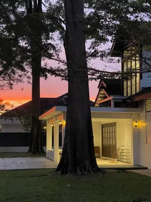 a house with a tree in front of a sunset at The Petrichor in Tupai