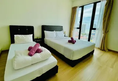two beds in a hotel room with pink pillows at Jazz Service Suite in Bagan Jermal