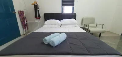 a bedroom with a bed with two pillows and a chair at Chalet Meroloh Kuala Kangsar in Kuala Kangsar
