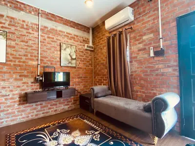 a living room with a couch and a brick wall at Homestay Damai D'Sawah in Kampong Parit Fourteen