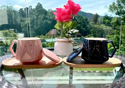 two cups and a vase with a flower on a glass table at Removed listing in Tanah Rata