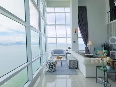 a living room with large windows and a couch at Fascinating Seaview Apartment at Maritime Penang in Jelutong