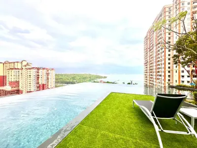 a swimming pool with chairs and a view of the water at Georgetown Seaview & Cityview Skypool with 2 Carpark in Jelutong